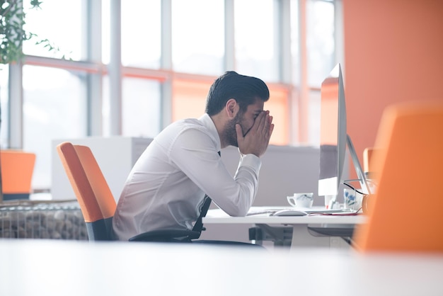 gefrustreerde jonge zakenman aan het werk op een desktopcomputer bij een modern opstartend kantoorinterieur