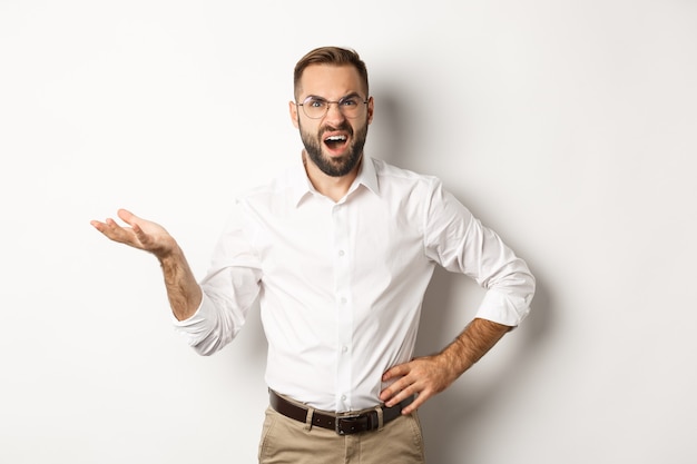 Gefrustreerde kantoormedewerker klagen, gebaren en teleurgesteld kijken, staande op een witte achtergrond.