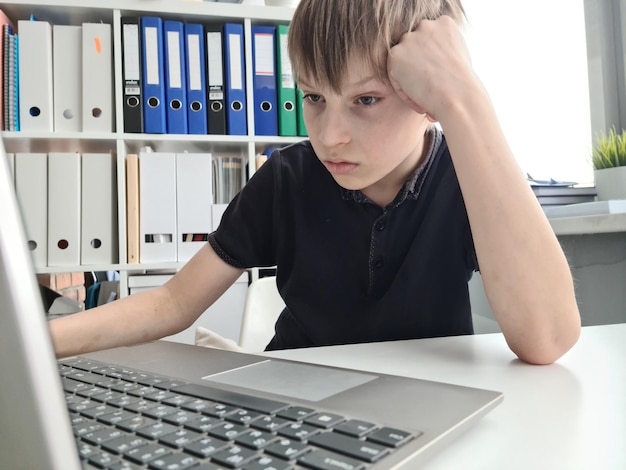 Gefrustreerde trieste schooljongen die laptop close-up bekijkt