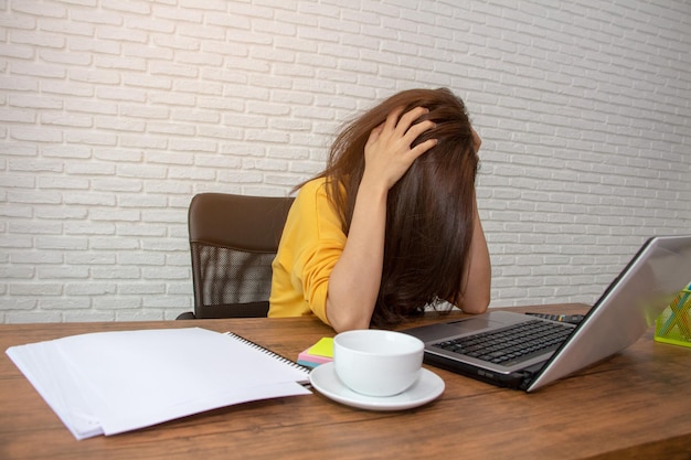 Gefrustreerde vrouw krabt haar hoofd terwijl ze op tafel zit