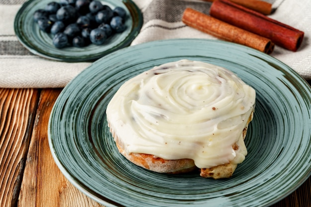 Geglazuurd cinnabonbroodje in groene plaat op houten lijst