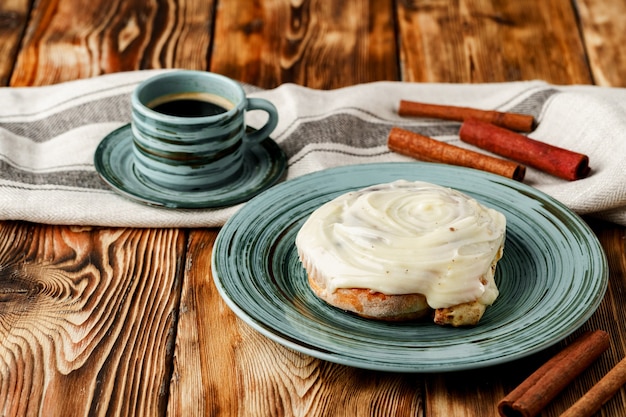 Geglazuurde cinnabon broodje in groene plaat op houten tafel close-up