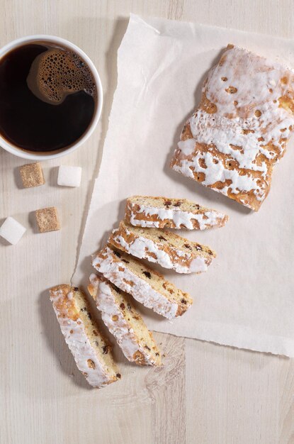 Geglazuurde peperkoek met rozijnen en kopje koffie op lichte houten ondergrond, bovenaanzicht