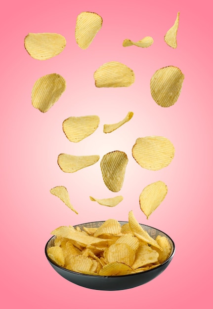 Gegolfde gebakken aardappelchips vallen in een grijze plaat op een roze achtergrond