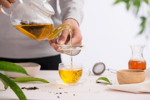 Gegoten uit een theepot kopje thee op een houten tafel