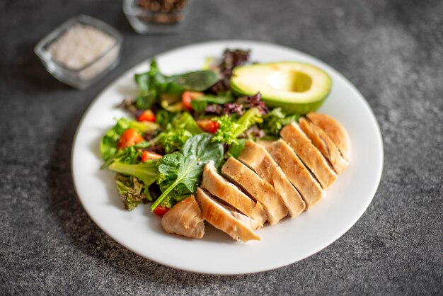 Gegrild kippenvlees en verse groentesalade van tomaat, avocadosla en spinazie