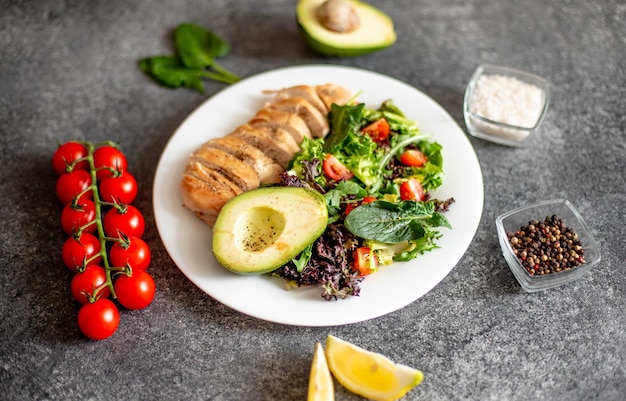 Gegrild kippenvlees en verse groentesalade van tomaat, avocadosla en spinazie