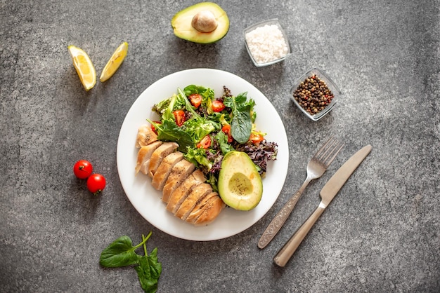 Gegrild kippenvlees en verse groentesalade van tomaat, avocadosla en spinazie