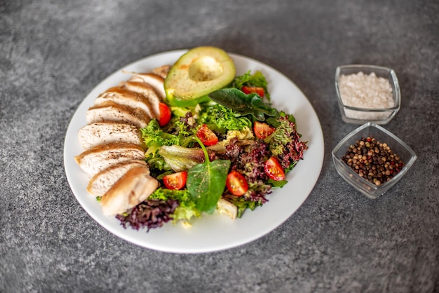 Gegrild kippenvlees en verse groentesalade van tomaat, avocadosla en spinazie