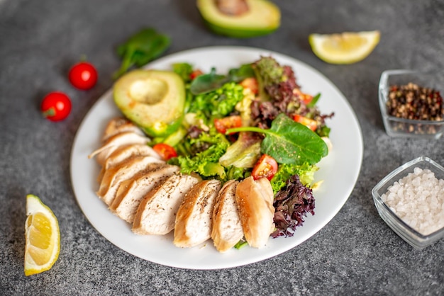 Gegrild kippenvlees en verse groentesalade van tomaat, avocadosla en spinazie