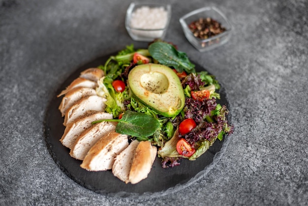 Gegrild kippenvlees en verse groentesalade van tomaat, avocadosla en spinazie