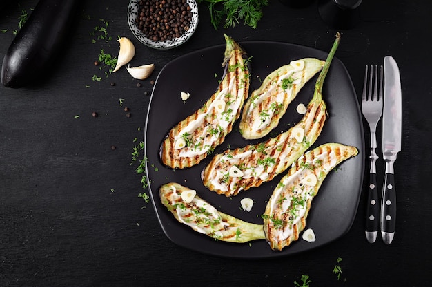 Gegrilde aubergine en yoghurtsaus op een zwarte achtergrond Gebakken aubergine Bovenaanzicht boven