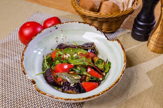 Gegrilde aubergine met verse en gedroogde tomaten, rucola en noten.