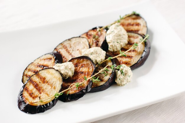 Gegrilde aubergines met deeg op een witte plaat