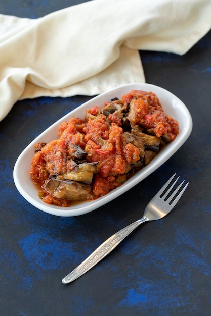 Gegrilde auberginesalade voorgerecht met tomatensaus met auberginesaus of saksuka Traditionele Midden-Oosterse meze naast het hoofdgerecht Lay-out op donker hout