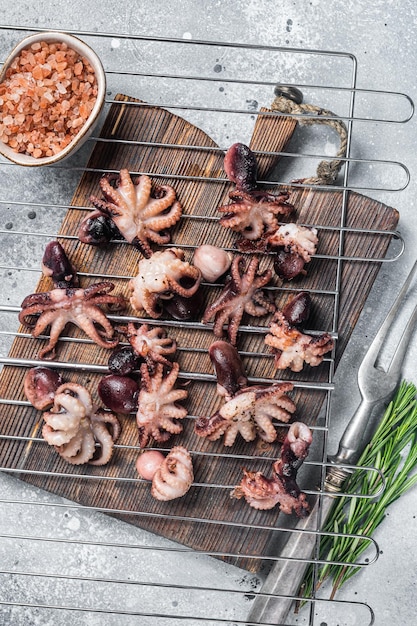 Foto gegrilde baby mini-octopussen op een grill grijze achtergrond bovenaanzicht