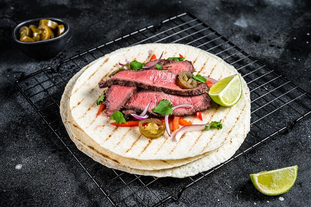 Gegrilde biefstuk Fajitas taco tortilla's met ui jalapeno en paprika Zwarte achtergrond bovenaanzicht