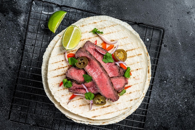 Gegrilde biefstuk fajitas taco tortilla's met ui jalapeno en paprika zwarte achtergrond bovenaanzicht