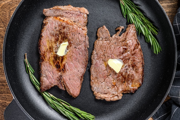 Gegrilde biefstuk hakken ronde biefstuk in een pan. houten tafel. Bovenaanzicht.