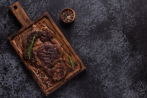 Gegrilde biefstuk met kruiden op een houten bord, bovenaanzicht.