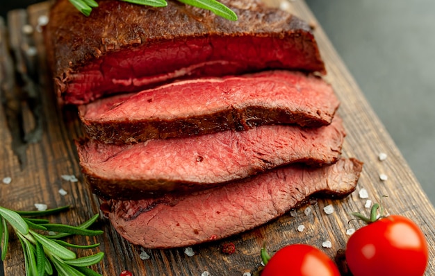 gegrilde biefstuk met kruiden op een snijplank, stenen achtergrond, bovenaanzicht