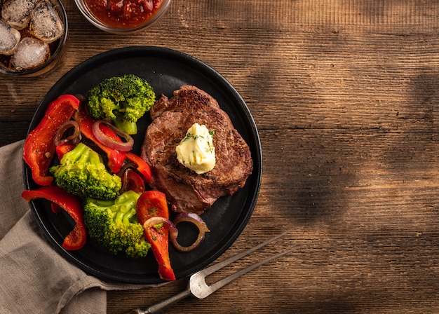 Gegrilde biefstuk met kruidenboter en groenten. Vlees met gegrilde paprika, broccoli en uien.