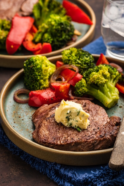 Gegrilde biefstuk met kruidenboter en groenten. Vlees met gegrilde paprika, broccoli en uien.