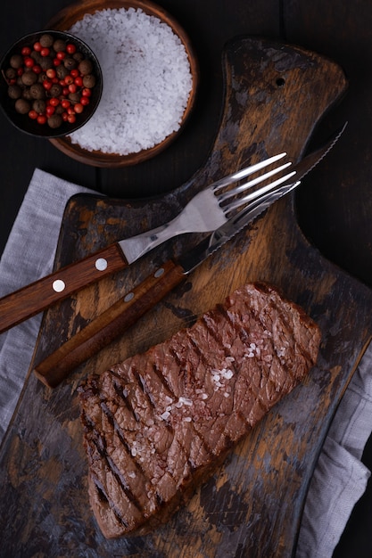 Gegrilde biefstuk met mes en vork op snijplank. Gekookt eten