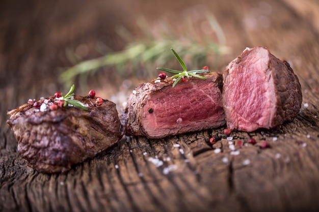 Gegrilde biefstuk met rozemarijn, zout en peper op oude snijplank. Ossenhaas biefstuk.