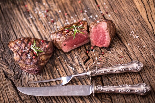 Foto gegrilde biefstuk met rozemarijn, zout en peper op oude snijplank. ossenhaas biefstuk.