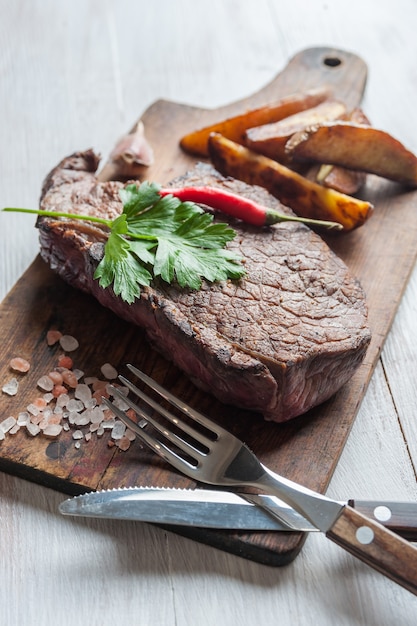 Gegrilde biefstuk op een houten bord. Heet ontmoet met groenten en kruiden