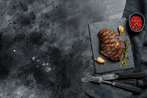 Gegrilde biefstuk op een stenen bord, gemarmerd rundvlees. zwarte achtergrond