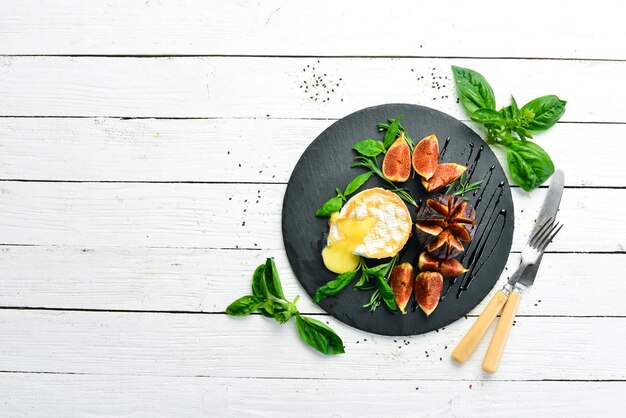 Gegrilde brie met vijgen en basilicum op een zwarte stenen plaat Bovenaanzicht Vrije ruimte voor uw tekst