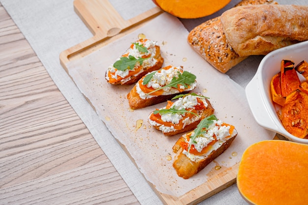 Gegrilde ciabatta bruschetta met gebakken pompoen, feta rucola en kruiden. gezonde herfstgebakken pompoensnack