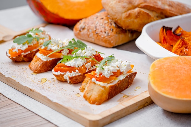 Gegrilde ciabatta bruschetta met gebakken pompoen, feta rucola en kruiden. gezonde herfstgebakken pompoensnack