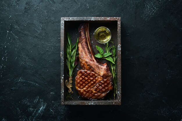 Gegrilde cowboy beef steak kruiden en specerijen op een zwarte stenen achtergrond Barbecue bovenaanzicht Vrije ruimte voor tekst