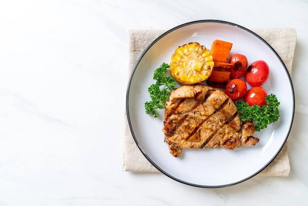 gegrilde en barbecue varkenshaasbiefstuk met mais, wortel en tomaten