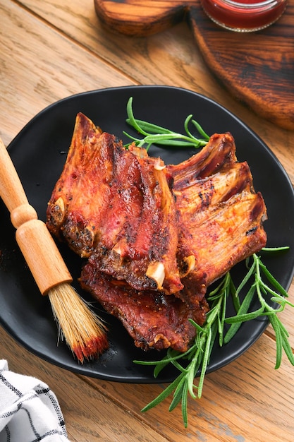 Gegrilde en gerookte varkensribbetjes met barbecuesaus op een oude vintage houten snijplank op oude houten tafel achtergrond Lekkere snack tot bier Amerikaans eten concept Bovenaanzicht