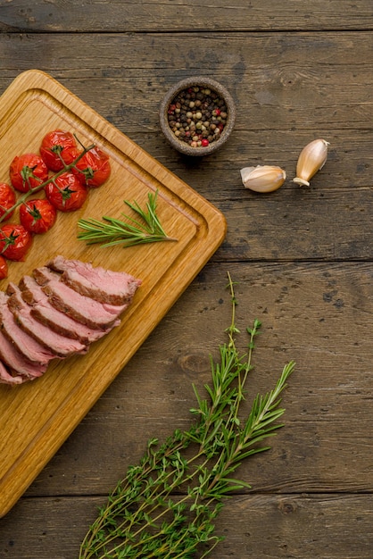 Gegrilde entrecote plakjes met tomaten tijm rozemarijn knoflook en peper op houten bord