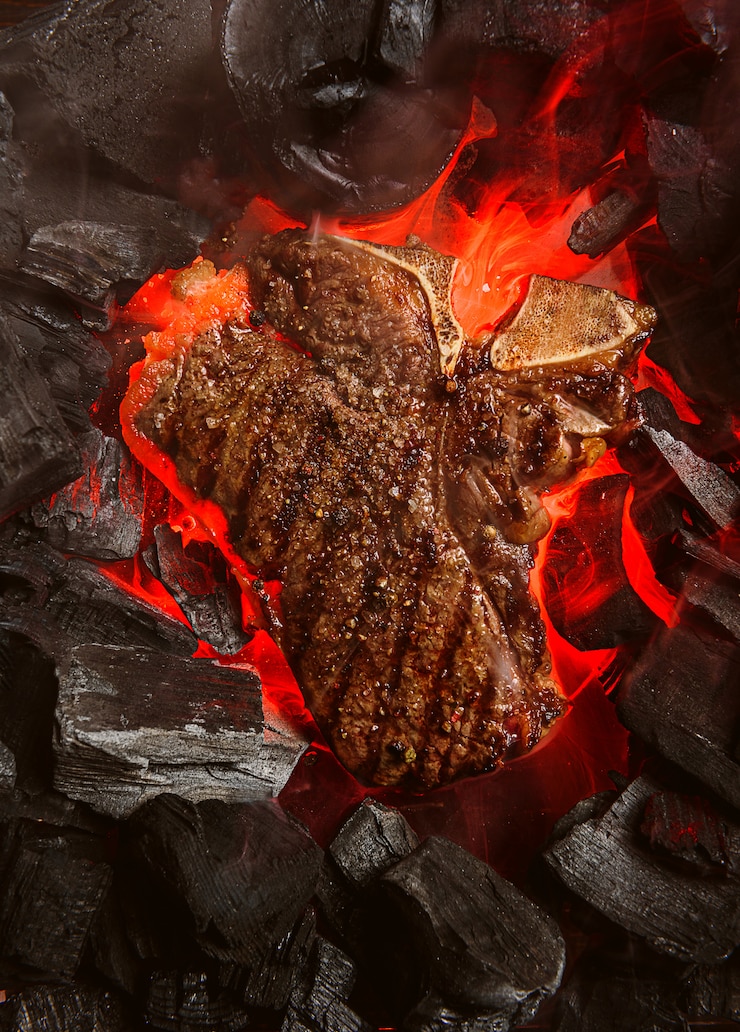 Foto gegrilde gemarmerde biefstuk met kolen en rook