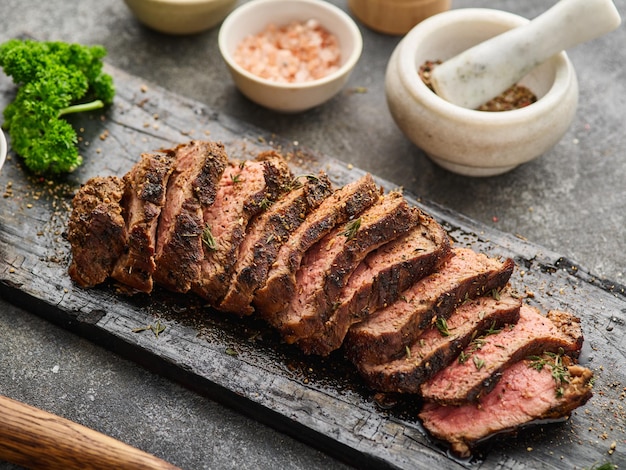 Gegrilde gesneden biefstuk op snijplank boven grijze tafel Ossenhaas steak Filet Mignon recept
