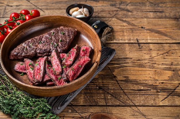 Gegrilde gesneden bovenmes of Denver beef steak in een houten plaat met kruiden.