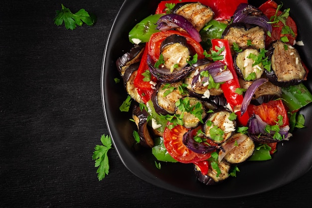 Gegrilde groenten aubergine paprika courgette rode ui tomaat met knoflook op een zwarte plaat Bovenaanzicht boven