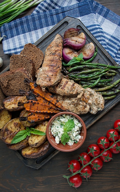 Gegrilde groenten en kipfilet worden geserveerd op een snijplank