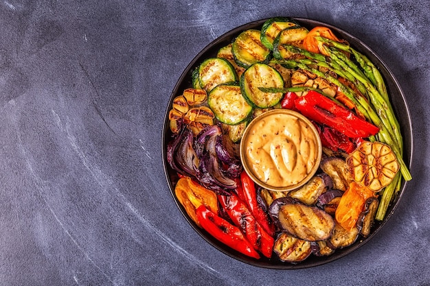 Gegrilde groenten op een bord met saus, bovenaanzicht.