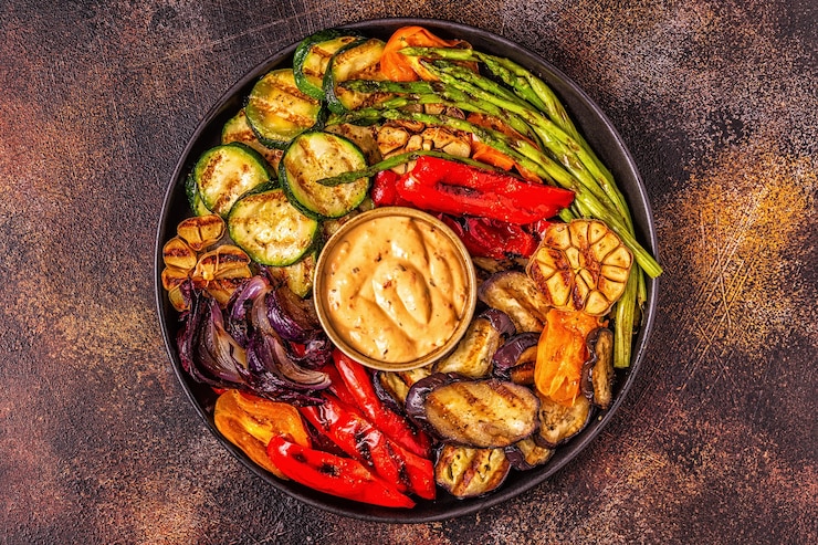 Foto gegrilde groenten op een bord met saus, bovenaanzicht.