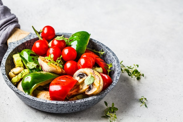 Gegrilde groenten (paprika, courgette, champignons en tomaten in de pan, witte achtergrond.