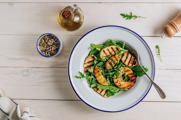 Gegrilde halloumi kaassalade met perzik en rucola.