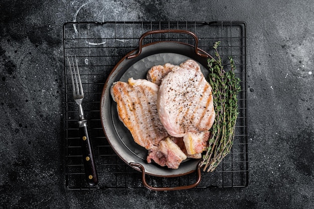 Gegrilde heerlijke pork chop steaks met kruiden en specerijen Zwarte achtergrond Top view