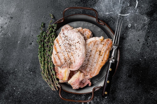 Gegrilde heerlijke pork chop steaks met kruiden en specerijen Zwarte achtergrond Top view